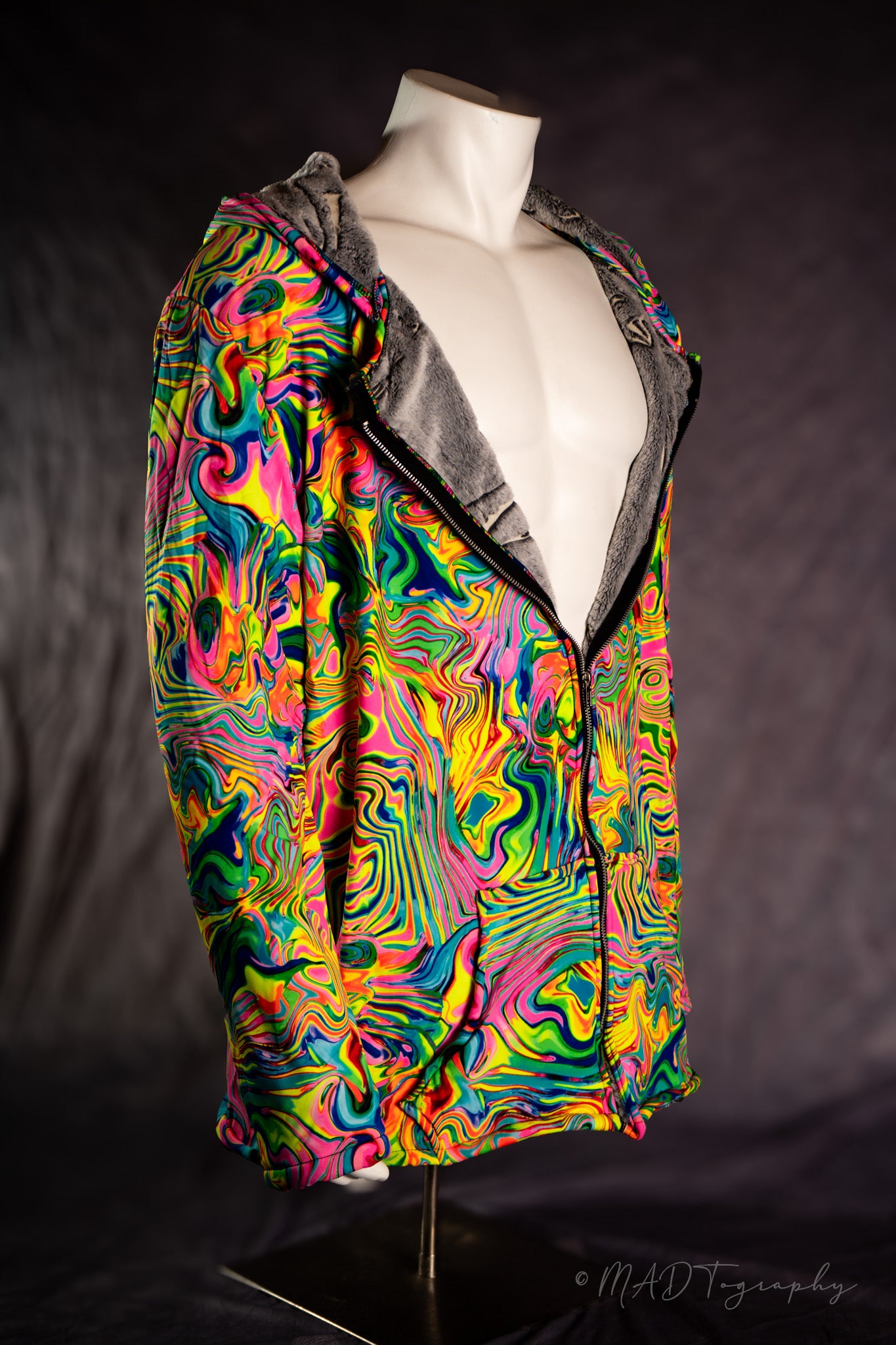 Colorful fluorescent rainbow jacket with a wavy pattern on a mannequin against a dark background