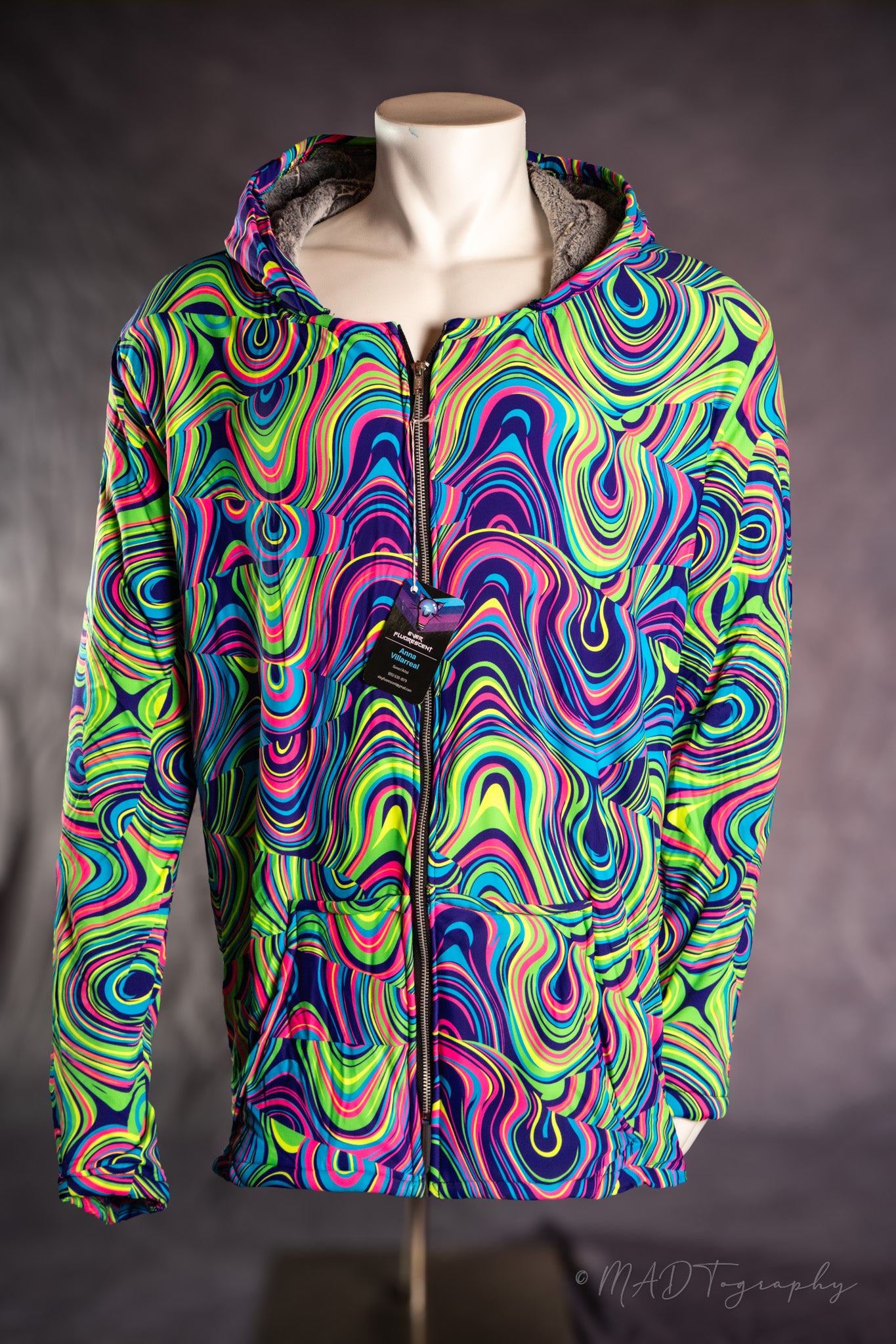 Colorful fluorescent psychedelic patterned jacket on a mannequin against a dark background