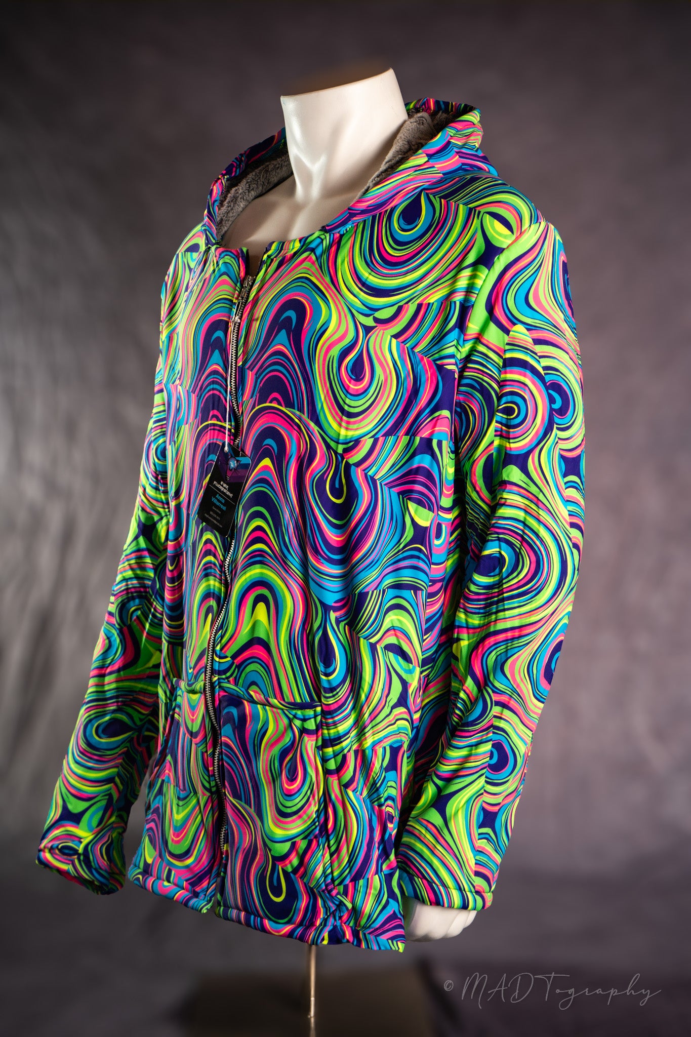 Colorful fluorescent psychedelic patterned jacket on a mannequin against a dark background