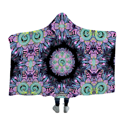 Person wearing a colorful mandala-patterned hooded blanket on a white background